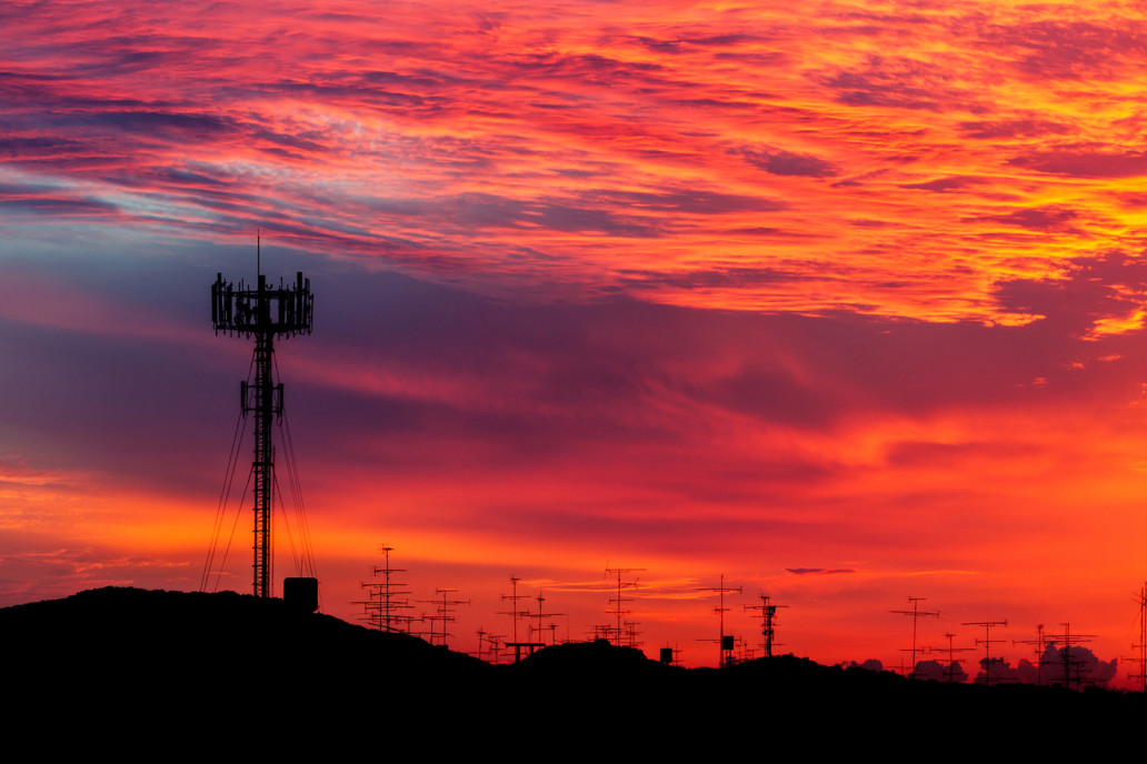 Telecommunications tower with sunset sky, silhouette