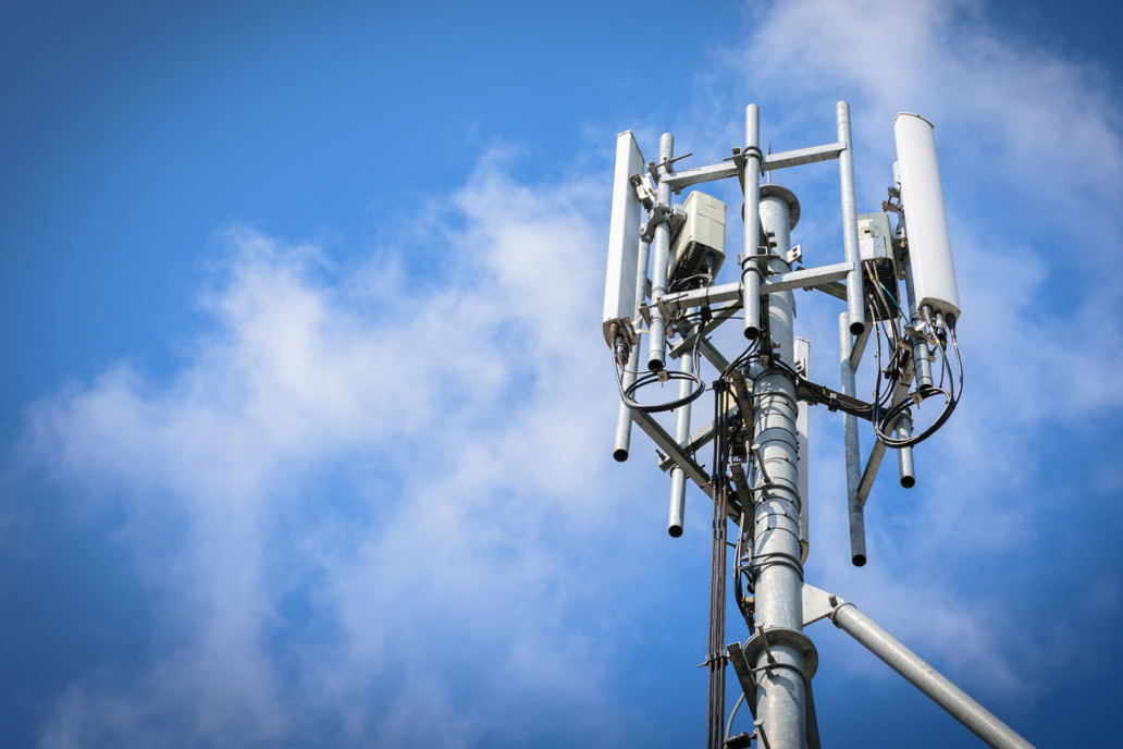 Telecommunications tower with antennas on blue sky with clouds